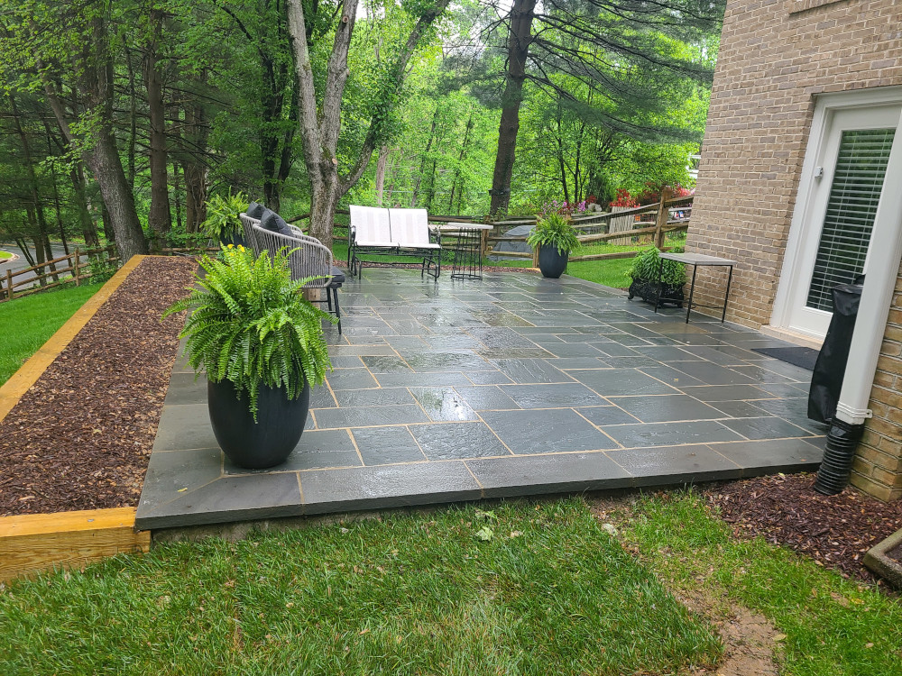 raised dark slab patio displayed with plants and furniture